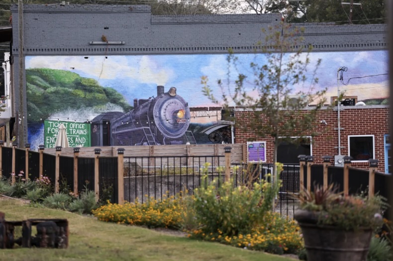 Photo of mural with train on side of downtown building.