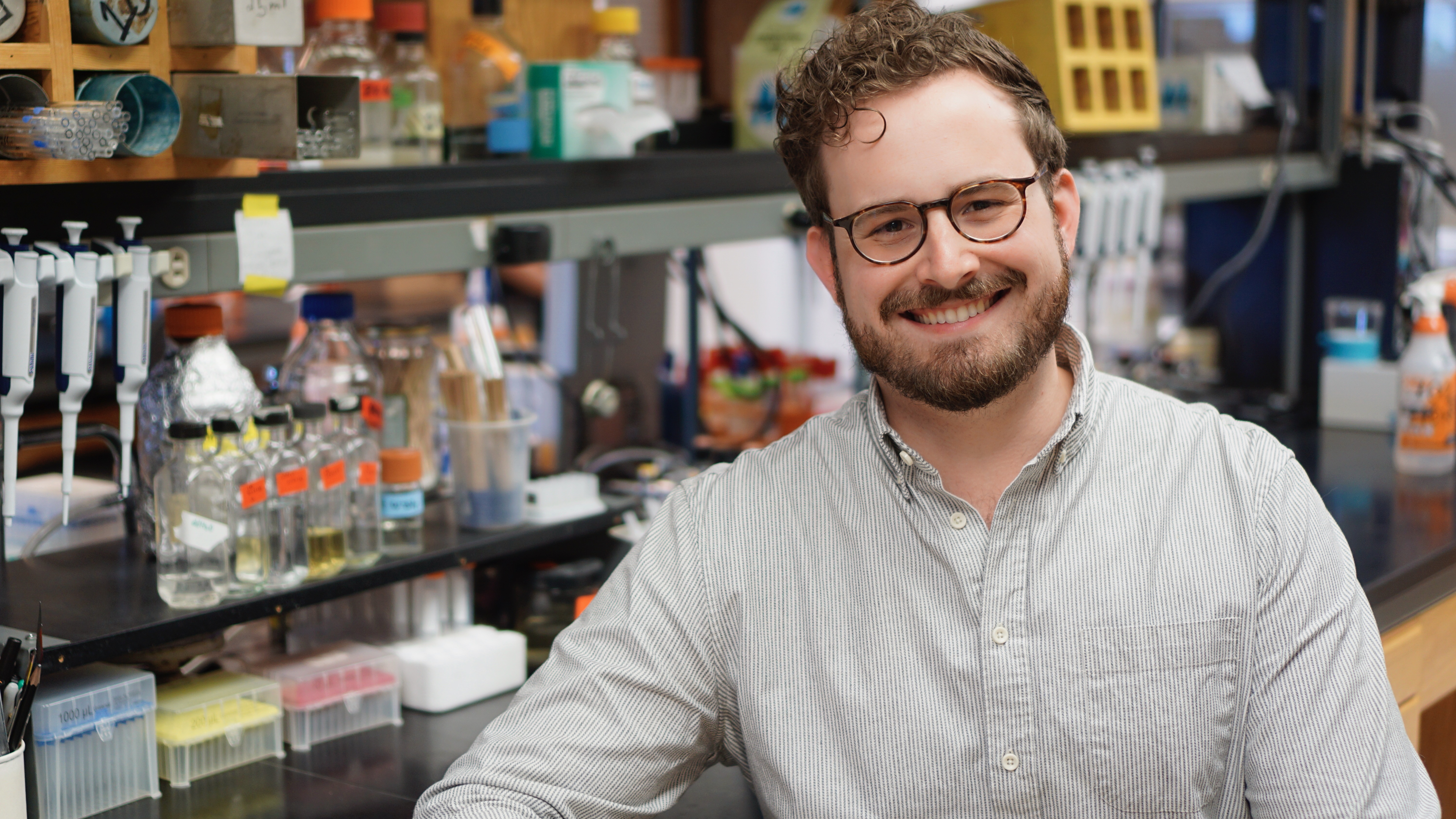 photo of man in laboratory, shelves and containers in background
