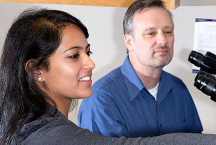 student with professor and microscope