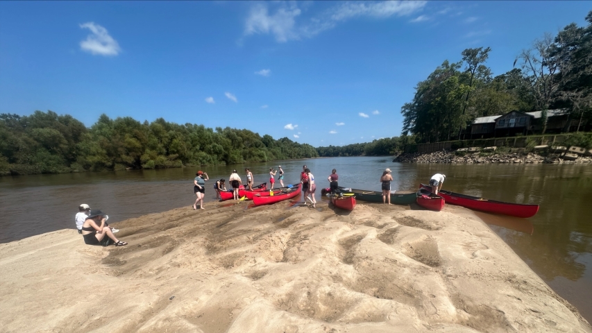photo of people on sandbar in river with kayaks, day
