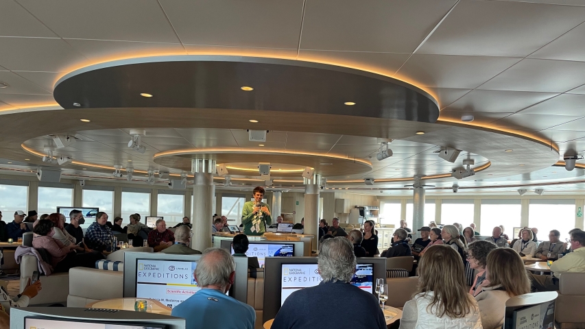 photo of people sitting with screens, speaker at center