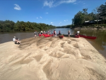 photo of people on sandbar in river with kayaks, day