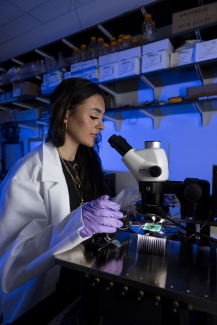 photo ofo woman with microscope, lab coat, gloves