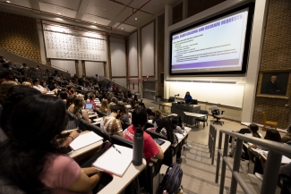 photo of lecture hall with students, screens