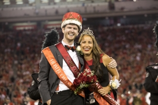 photo of couple with crowns at football stadium, night, blurred crowd background