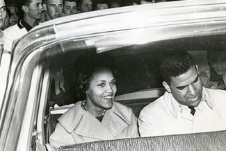 b/w photo of two people in a car, from outside