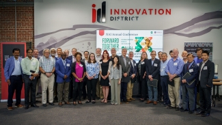 group photo of 31 people, indoors, sign in background