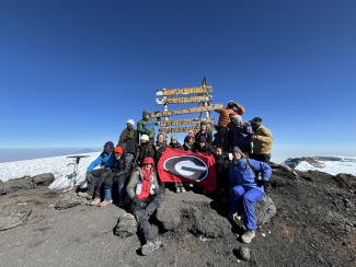 group photo of people on mountain top, with signs, snow