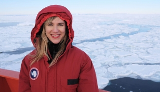 photo of woman in red coat, ice-coverd sea in background