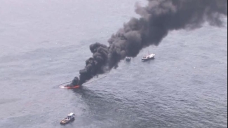 aerial photo of black smoke rising from the ocean water