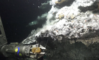 photo of smoke plume in water, mechanical arm in foreground