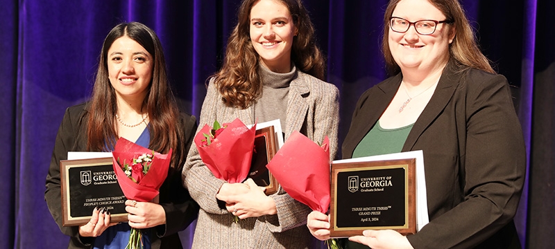 photo of three women holding plaques at ceremony