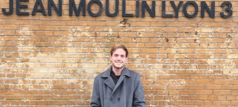 photo of man in front of wall with letters in black