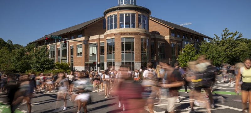 photo of blurred people crossing an intersection, with blue sky