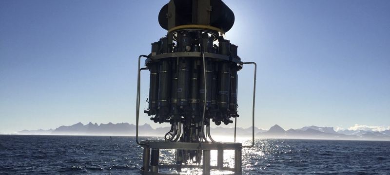 photo of scientific device suspended about sea, mountains and sky in background