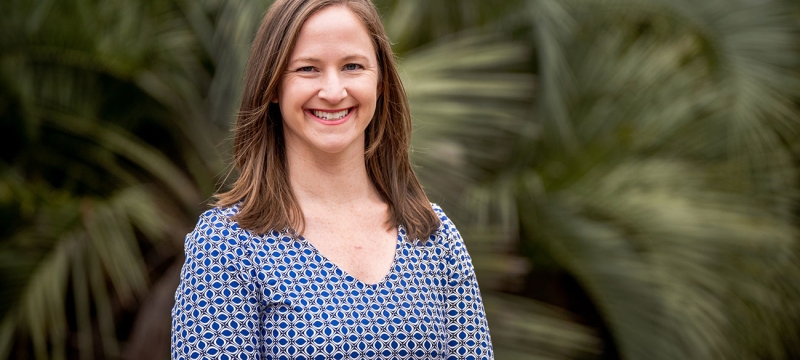 photo of woman with palm fronds in background 