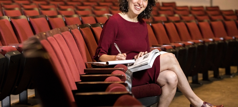 photo of woman seated in auditorium, writing