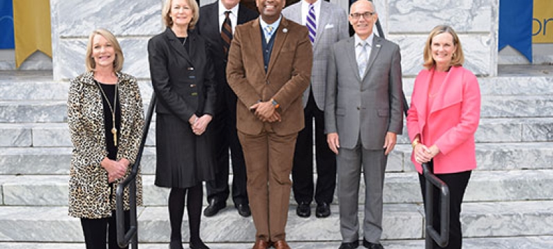 Outdoor photo of seven people on steps of a building