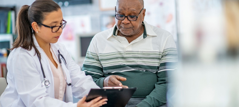 photo of doctor with patient, both looking at clipboard