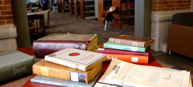 photo of books stacked on a table in a library 