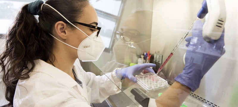 photo of scientists in lab with mask, gloves, pipette