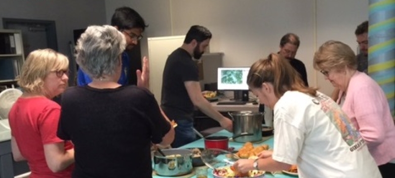 photo of people making plates of food around a table