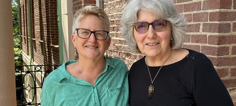 photo of two people, building in background, day