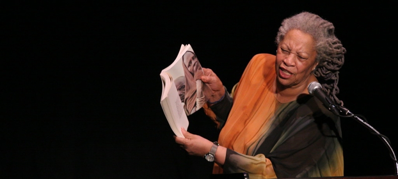 photo of woman reading aloud at a podium with mic