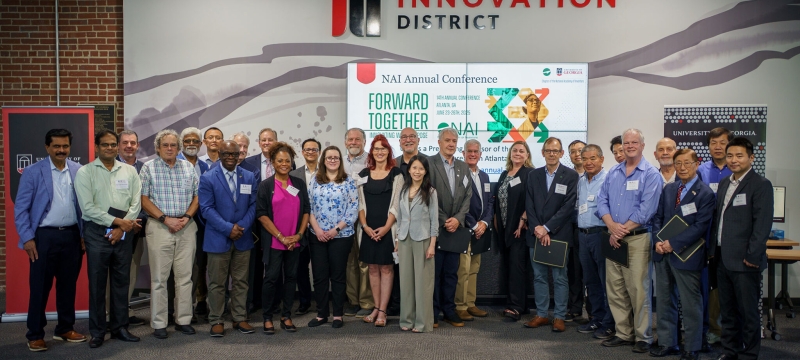 group photo of 31 people, indoors, sign in background