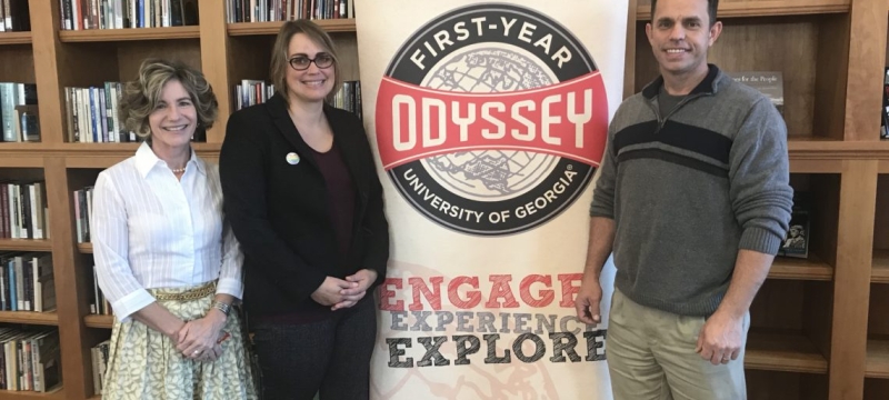 photo of three people with banner and book shelves
