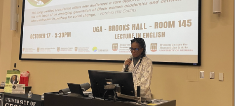 photo of speaker at podium, with screen and text