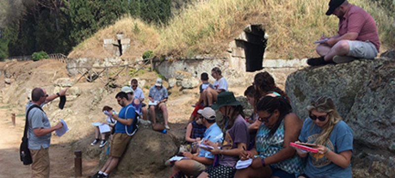 students with professor at ancient tomb opening