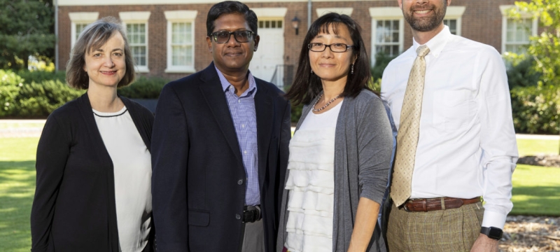 photo of four people, with Old College in background
