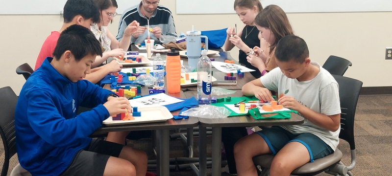 photo of 7 people at a table assembling materials