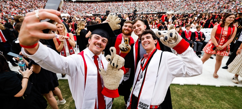 photo of people taking selfies in stadium, crowd in background