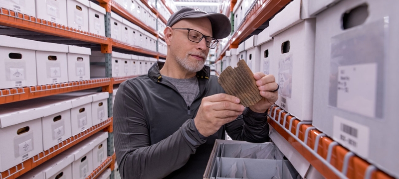 photo of man in aisle of shelves with boxes