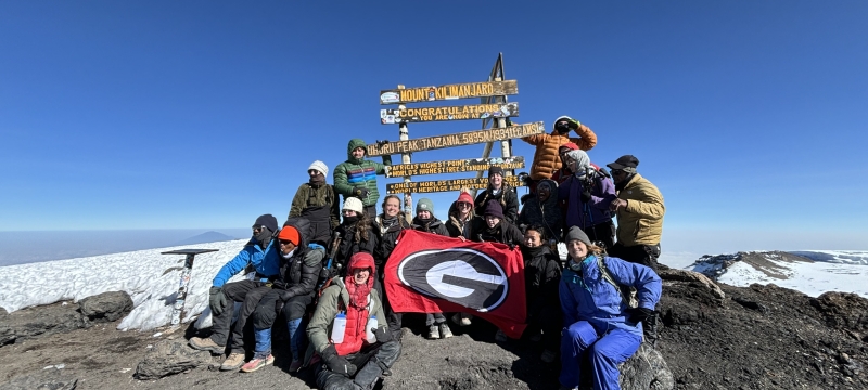 group photo of people on mountain top, with signs, snow