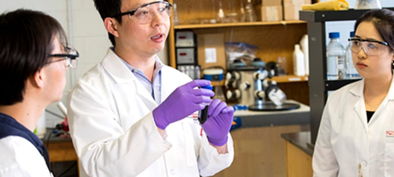 photo of man and students in lab coats