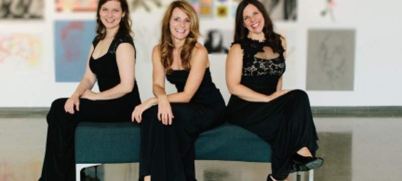 photo of three women on a bench, with paintings
