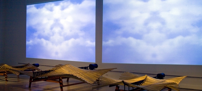 photo of gallery installation with squares of sky and clouds, wood and steel sculptures