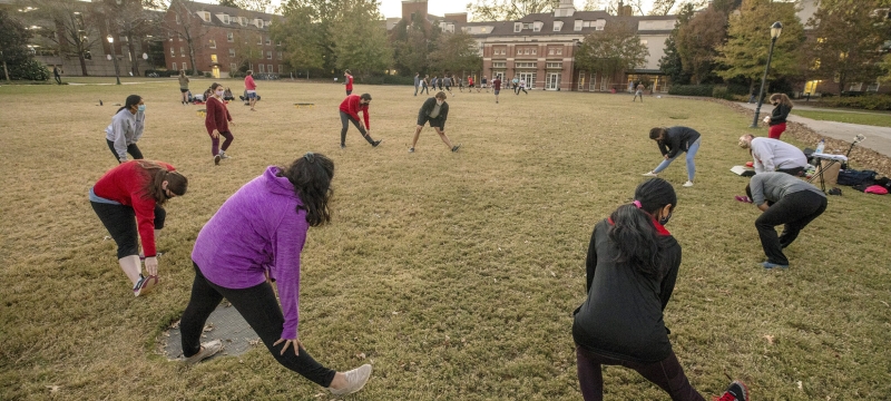 photo of a group of people, in a circle stretching 
