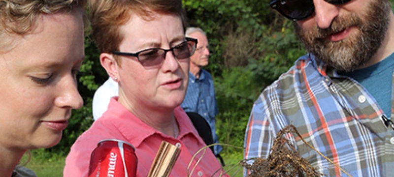 photo of two women and man looking at peanut plant