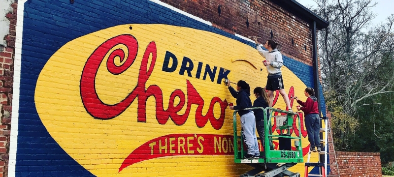 photo of students with lift, painting mural