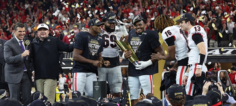 photo of football players on stage, with confetti and trophy