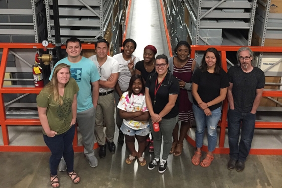 Photo of ten people in a warehouse interior