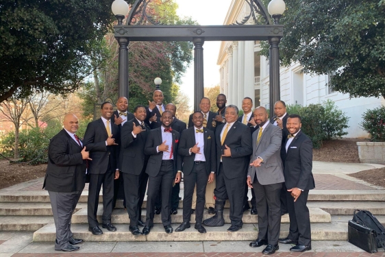 photo of men in suits in front of Arch, day