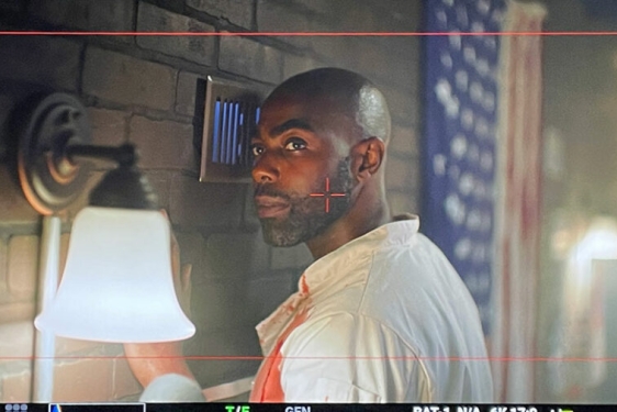 film still of man, with wall light and flag