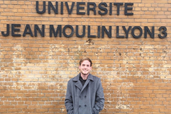 photo of man in front of wall with letters in black