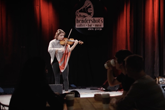 still photo of woman playing violin on a club stage