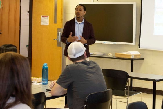 photo of people in a classroom, two standing 